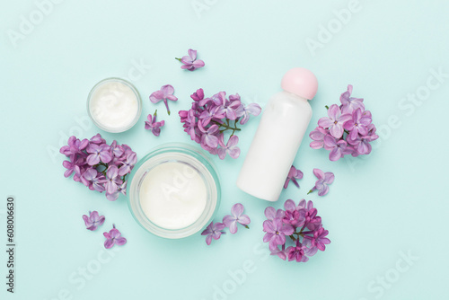 Composition with cosmetic bottles and flowers on color background  top view