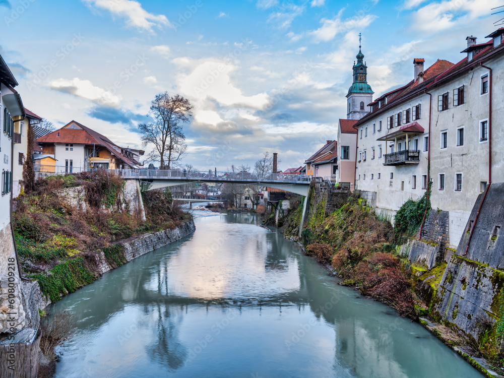 Selca Sora river and riverside old buildings during a dramatic sunset clouds in Skofja Loka village, Slovenia