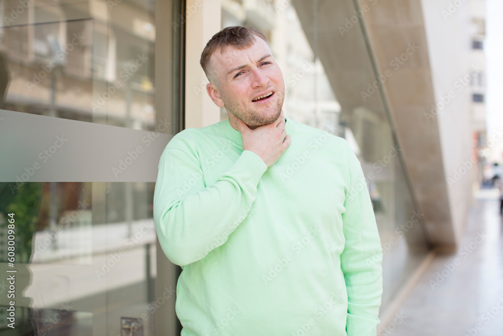 handsome man feeling ill with a sore throat and flu symptoms, coughing with mouth covered handsome man feeling ill with a sore throat and flu symptoms, coughing with mouth covered