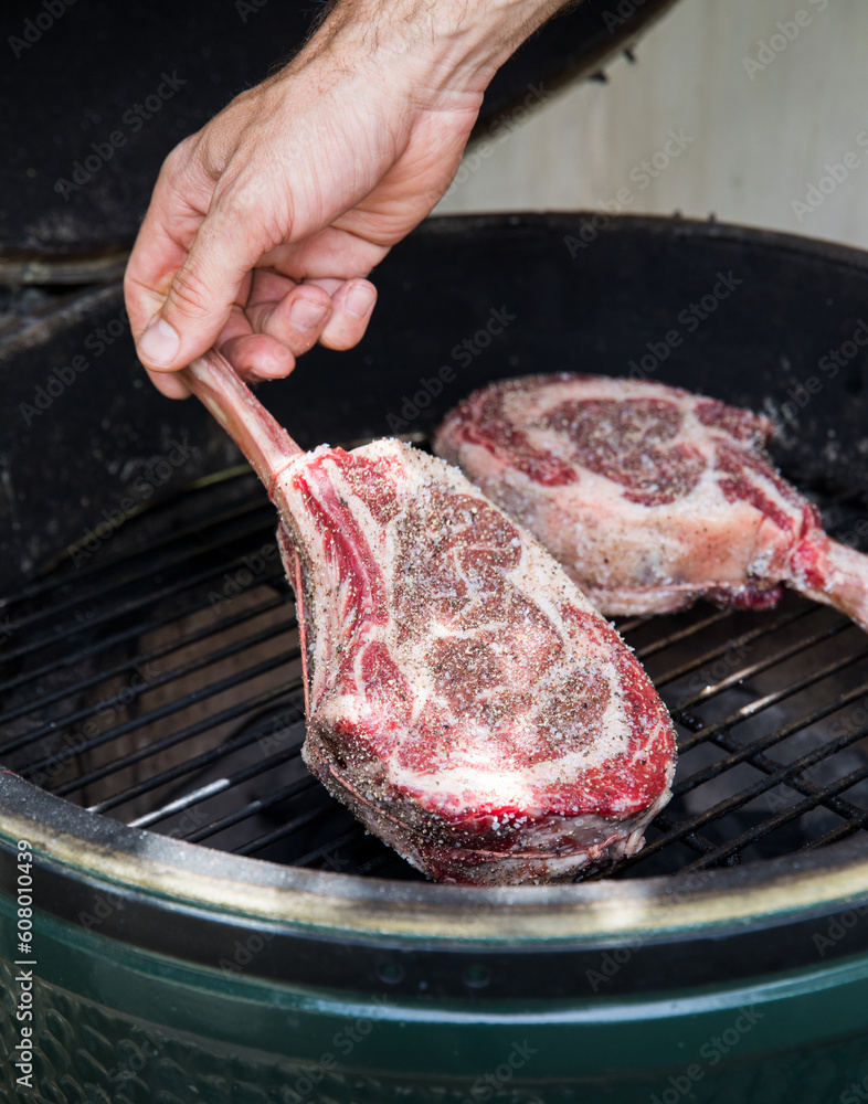 Placing a seasoned ribeye steak on the charcoal Konro Grill. Stock