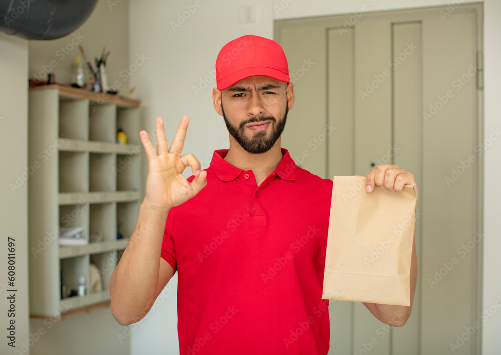 young adult man feeling happy, showing approval with okay gesture. deliveryman concept young adult man feeling happy, showing approval with okay gesture. deliveryman concept