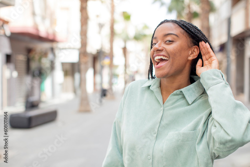 afro pretty black woman looking happy, listening, trying to hear a secret conversation or gossip, eavesdropping