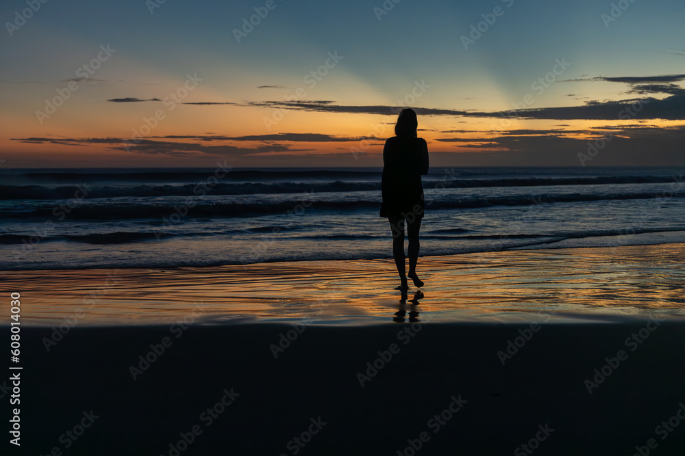 woman walking on the beach at sunset