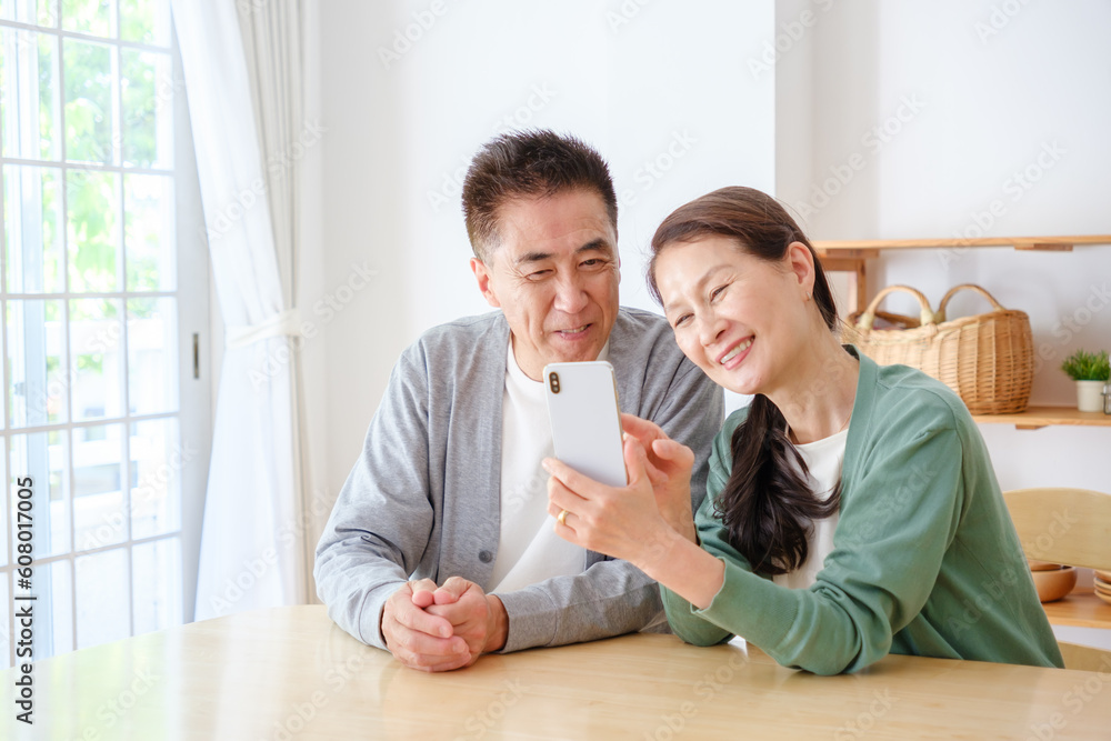 Fototapeta premium リビングでスマートフォンを使うシニア夫婦