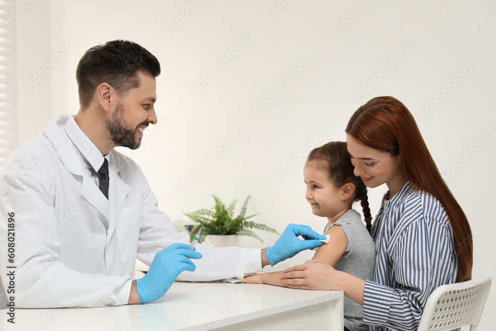 Children's hepatitis vaccination. Mother with her daughter in clinic. Doctor giving injection to little girl Children's hepatitis vaccination. Mother with her daughter in clinic. Doctor giving injection to little girl