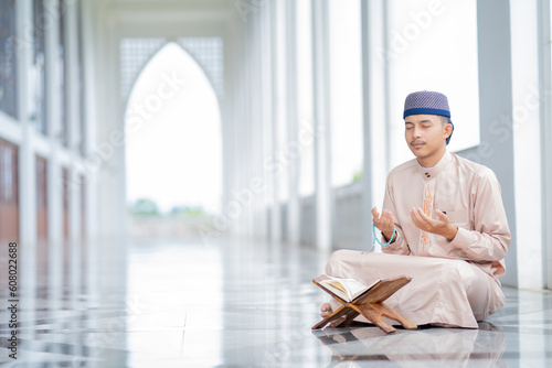 Photography An Asian Muslim man is sitting and reading the Quran