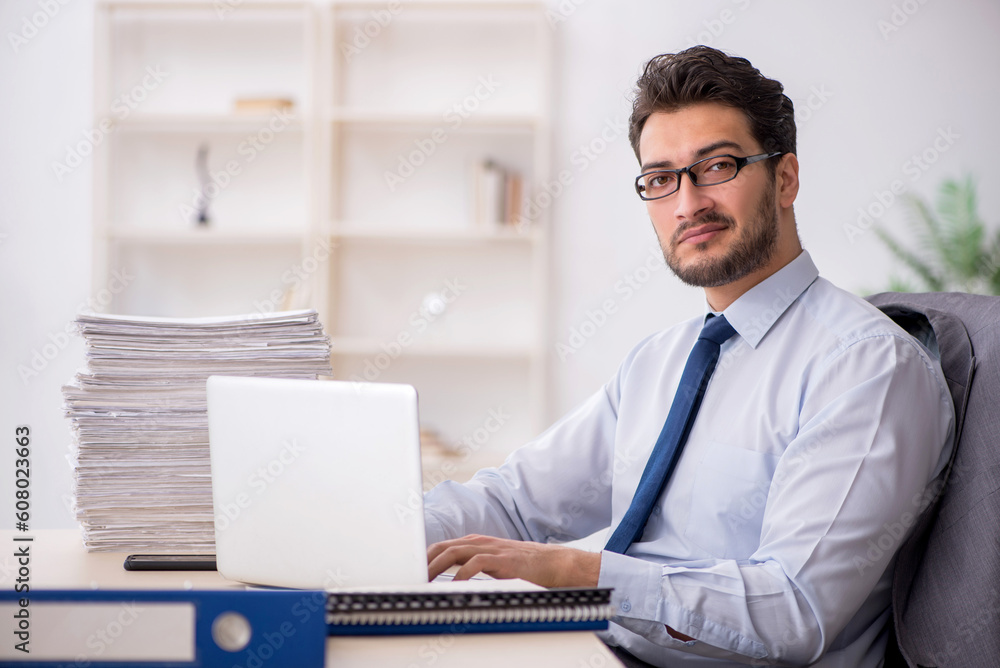 Young male employee and too much work in the office Young male employee and too much work in the office