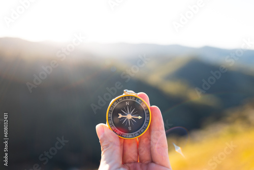 Foto Hand holding a compass to guide yourself along the path or trail with mountains and sunset in the background