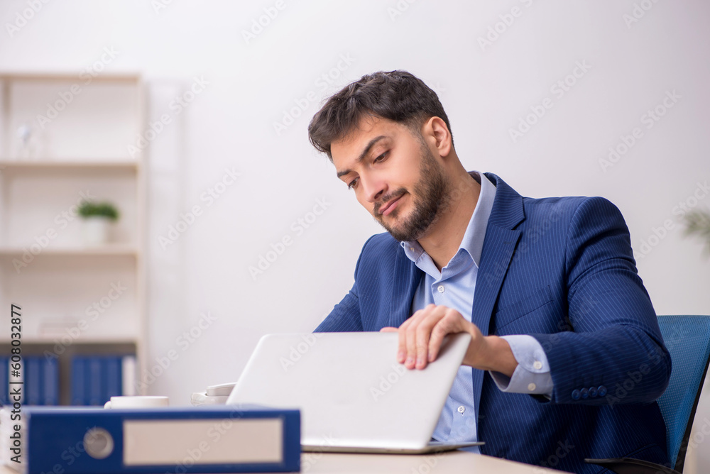 Young male employee sitting at workplace Young male employee sitting at workplace