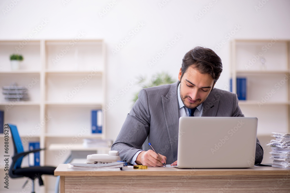 Young male employee and too much work in the office Young male employee and too much work in the office