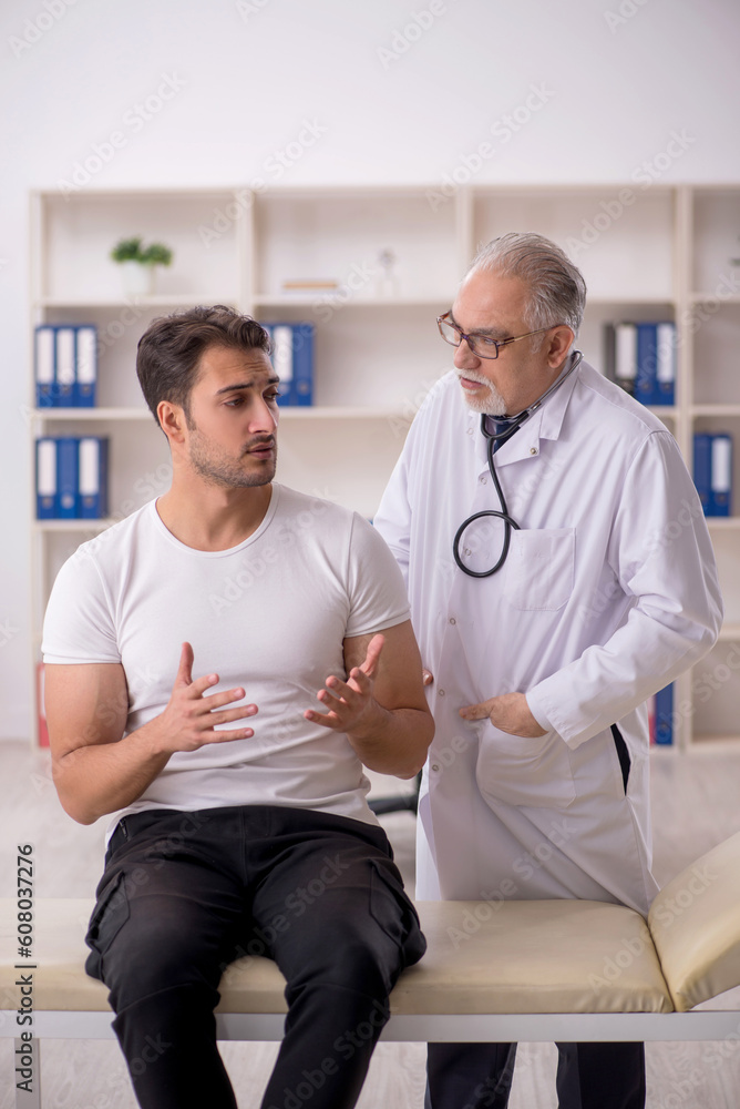 Fototapeta premium Young male patient visiting old male doctor