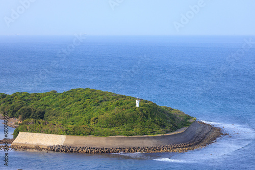 Concrete sea wall protects coastline on small green island with lighthouse photo