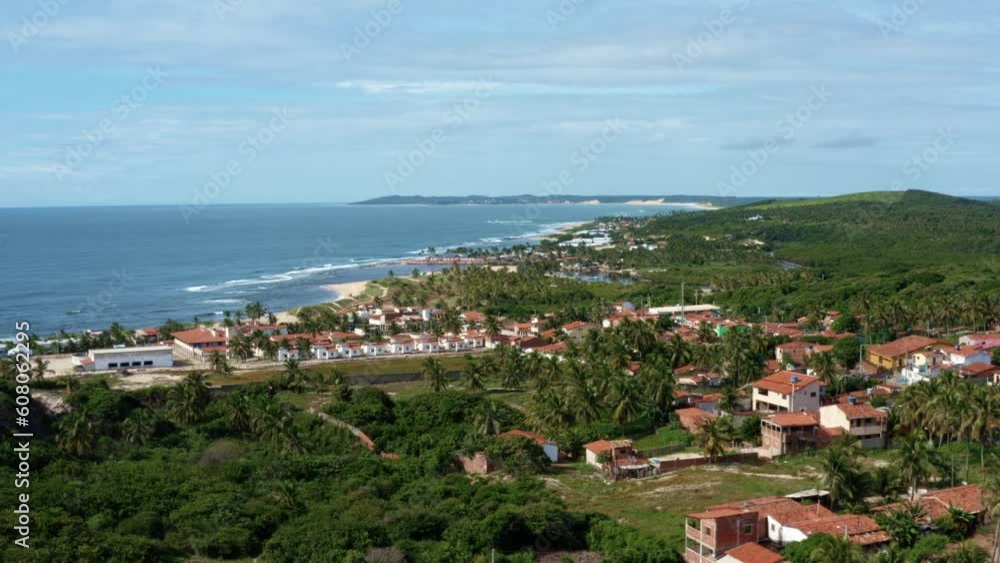 Left truck tilt up aerial drone wide shot of the tropical village of Sibauma in Tibau do Sul, Rio Grande do Norte, Brazil with palm trees, jungle, rural homes, dirt roads, and a stunning coastline Left truck tilt up aerial drone wide shot of the tropical village of Sibauma in Tibau do Sul, Rio Grande do Norte, Brazil with palm trees, jungle, rural homes, dirt roads, and a stunning coastline