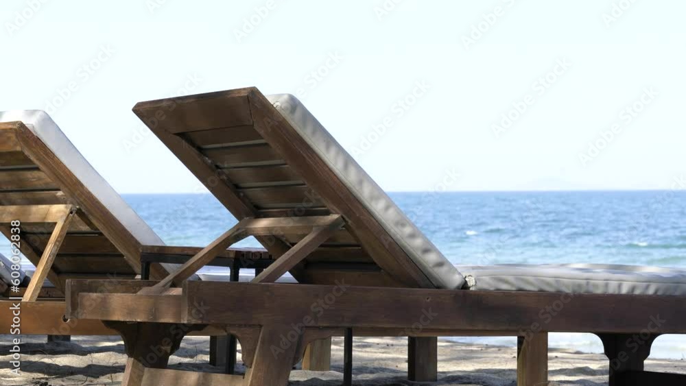 Behind two sun beds on the beach, perspective view, background of the blue sea and bright sky. Behind two sun beds on the beach, perspective view, background of the blue sea and bright sky.
