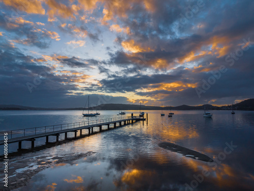 Aerial sunrise over the water with low cloud cover, boats and reflections © Merrillie