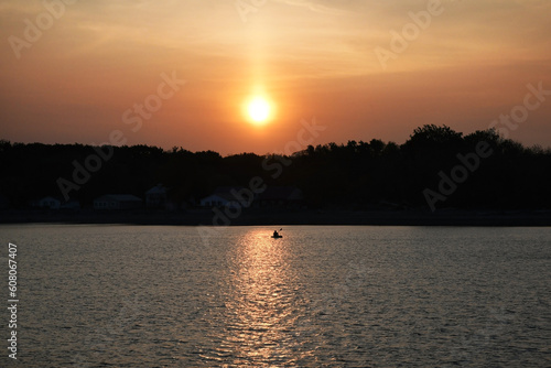 Sun over river with kayak silhouette and orange sky, Cattaraugus Creek, New York photo