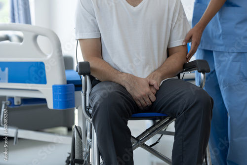 Rehabilitation specialist or physiotherapist giving physical training instruction to a male patient with scrotal pain in a wheelchair at a rehabilitation center health insurance concept.