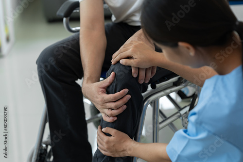 Female physiotherapist working examining injured knee and leg of male patient in wheelchair, giving advice, treating pain in clinic, physiotherapy concept, health insurance.