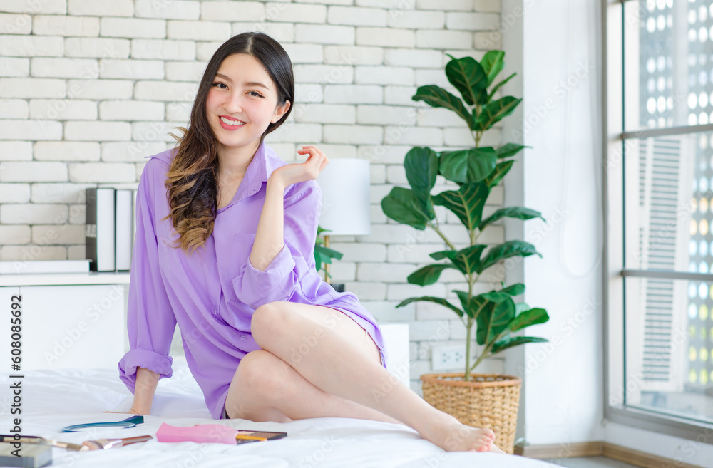 Millennial Asian cheerful happy beautiful female model in casual long sleeve shirt outfit sitting smiling resting relaxing posing have make up cosmetics lipstick brushing on bed in bedroom Millennial Asian cheerful happy beautiful female model in casual long sleeve shirt outfit sitting smiling resting relaxing posing have make up cosmetics lipstick brushing on bed in bedroom