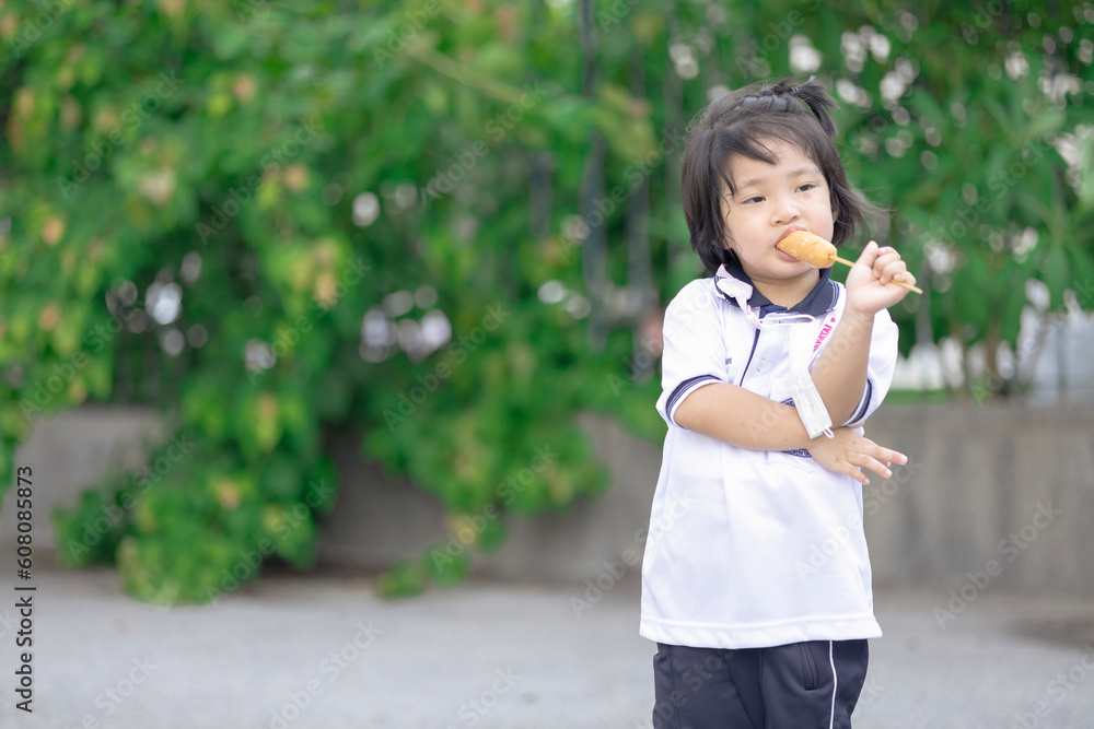 Portrait of a cute little girl. Photo taken outdoors in the garden. Kid eat hotdog Portrait of a cute little girl. Photo taken outdoors in the garden. Kid eat hotdog