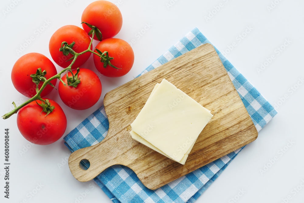 Slicing cheese into pieces and tomato on table 