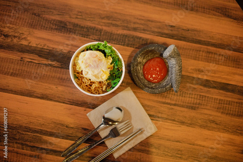 Noodles with egg topping and chili sauce next to a spoon and fork