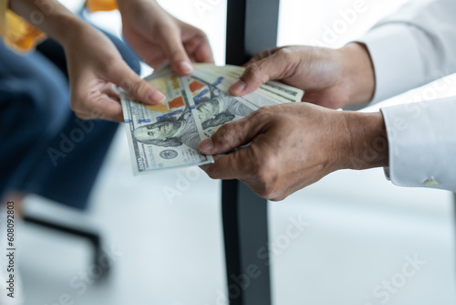 Businesswoman hand holding bribe money to government officials sign contracts for business projects, put money under envelope, ideas of corruption and anti-bribery.