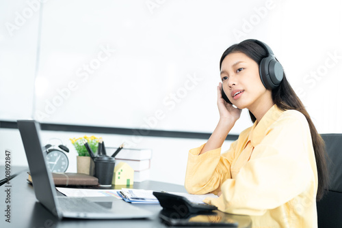 Attractive young Asian business woman relaxing from work during break listening to music and having fun. on white background