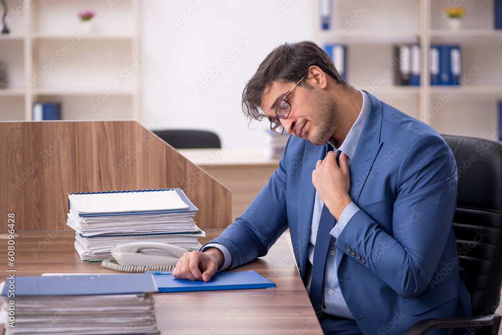 Young male employee and too much work in the office Young male employee and too much work in the office
