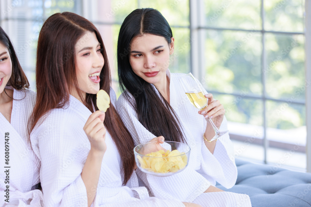 Closeup Asian cheerful happy female in casual white clean bathrobe outfit sitting smiling holding drinking sparkling champagne glass and snack bowl party together with friends in spa resort. Closeup Asian cheerful happy female in casual white clean bathrobe outfit sitting smiling holding drinking sparkling champagne glass and snack bowl party together with friends in spa resort.