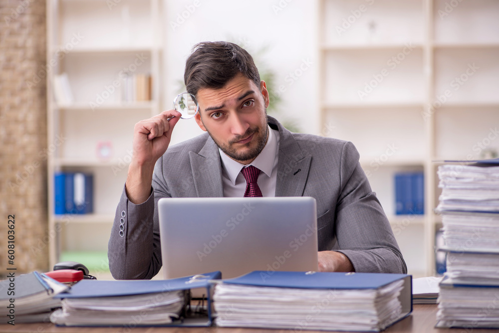 Young male employee and too much work in the office Young male employee and too much work in the office
