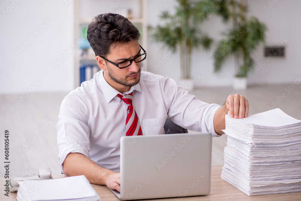 Young male employee and too much work in the office Young male employee and too much work in the office