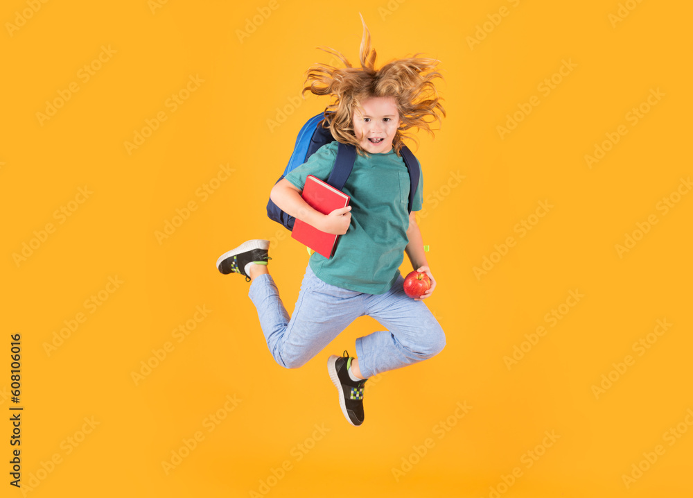 Back to school. Full length body of cheerful school child jumping running back to school isolated over yellow background.