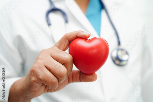 Asian woman doctor holding red heart for health in hospital.