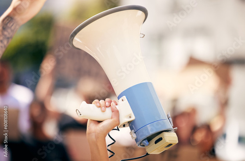 Hand, megaphone closeup and outdoor protest for change, justice or environment for people together in city. Bullhorn, loudspeaker and zoom for communication, speech or leadership for politics on road