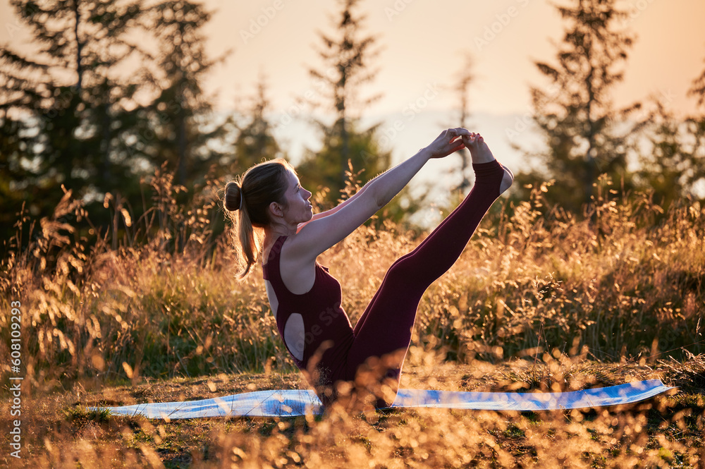 Sporty girl doing boat pose. Young female doing yoga exercises at dawn. Practicing yoga on fresh air. Sporty girl doing boat pose. Young female doing yoga exercises at dawn. Practicing yoga on fresh air.