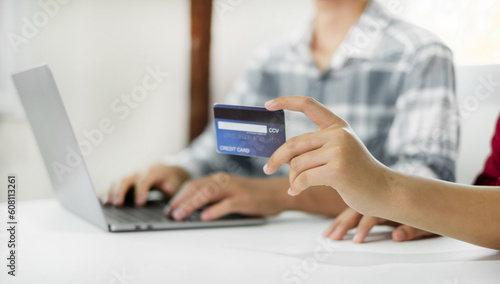 E-commerce Concept. Happy couple holding credit card enjoying doing online shopping and using laptop enter their card number in-app to purchase and payment in internet store