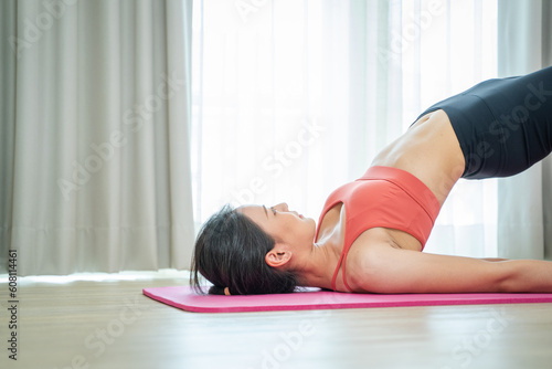 Beautiful woman exercising with yoga on fitness mat at home.