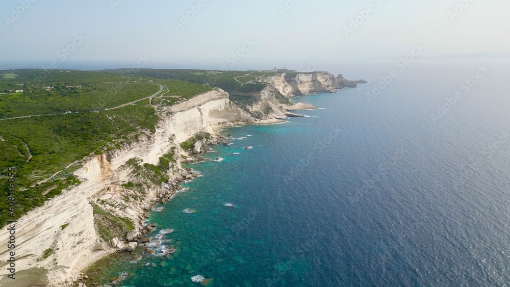 The Imposing Sentinel: Fog-Clad Cliffs and Azure Sea of Bonifacio Coast, Corsica, Guarded by Pertusato semaphore