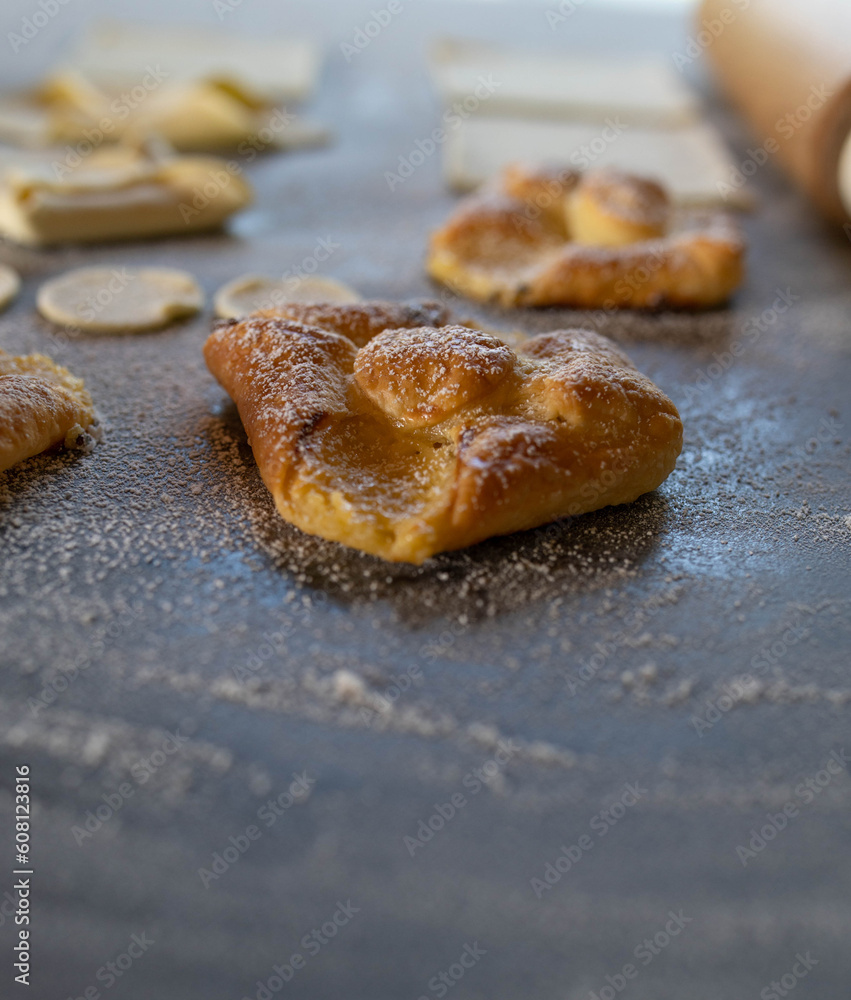 Puff pastry fresh baked with sour cream filling on a table with unbaked dough Puff pastry fresh baked with sour cream filling on a table with unbaked dough