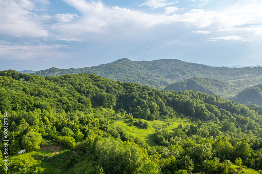Aerial landscape over a green tree forest. Spring sunset aerial view over hills and mountains sight.