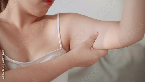 Close up of Chubby woman pinching upper arm fat. weight loss concept.