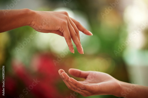Hands, love and people with a reaching gesture in an outdoor green garden or park in nature. Connection, romantic and closeup zoom of a couple for support, romance or touch together outside. © Daiyaan P/peopleimages.com