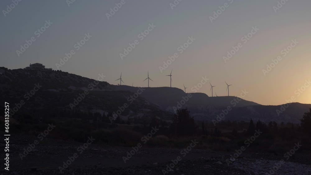Wide shot sunset in mountains with windmills producing power. Twilight on Cyprus landscape with no people outdoors Wide shot sunset in mountains with windmills producing power. Twilight on Cyprus landscape with no people outdoors