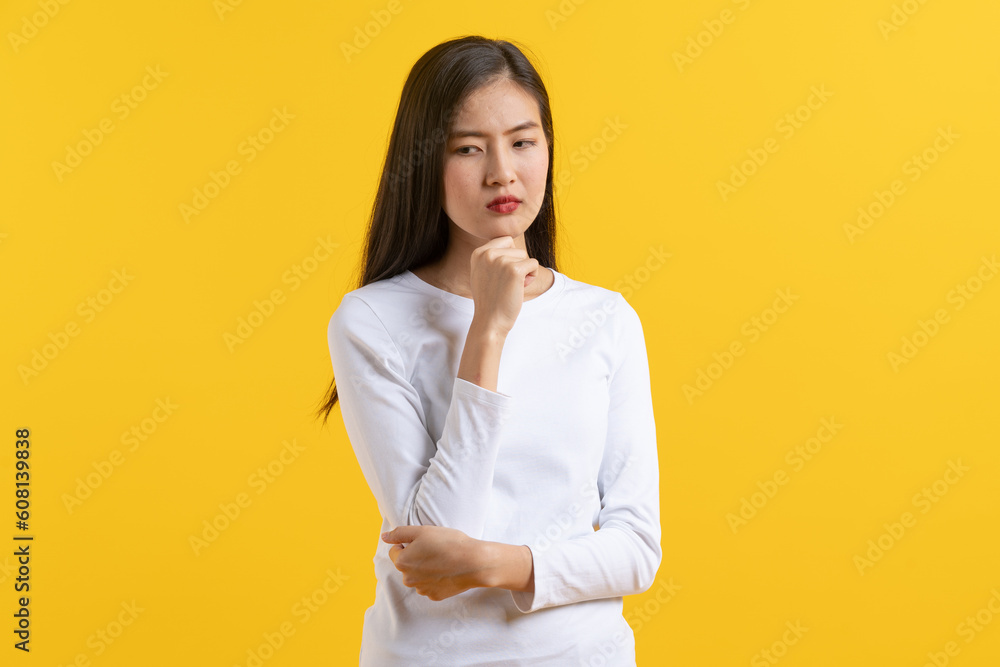 Cute asian young woman in white casual dress looking up and thinking / imagination isolated on yellow background in studio.banner size. Cute asian young woman in white casual dress looking up and thinking / imagination isolated on yellow background in studio.banner size.