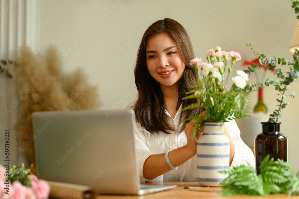 Smiling young woman flower shop owner checking orders from client on laptop. Floristry and small business concept Smiling young woman flower shop owner checking orders from client on laptop. Floristry and small business concept