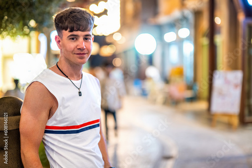 Portrait of handsome young man wearing sleeveless t-shirt looking at camera on city street at night. © Bojan
