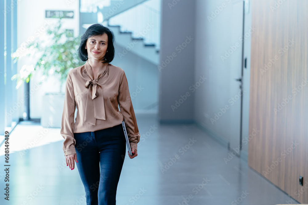 Indoor portrait of manager, coach, lawyer, consultant, customer support, designer. Middle aged brunette woman 40 50 years old in lobby.