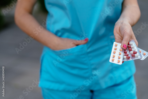 Close up of female doctor's in blue uniform hands holding blister with pills for treatment, health care and medication concept.