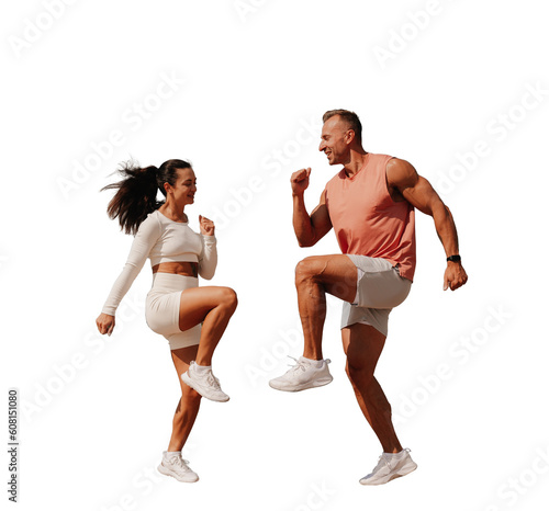 Young brunette woman in white sportswear jumping with trainer against transparent background. Sport, fitness, exercise. Tanned European strong man at exercise with wife.